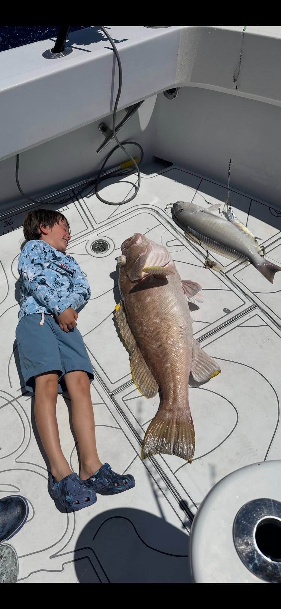 A young angler with a grouper and kingfish on deck