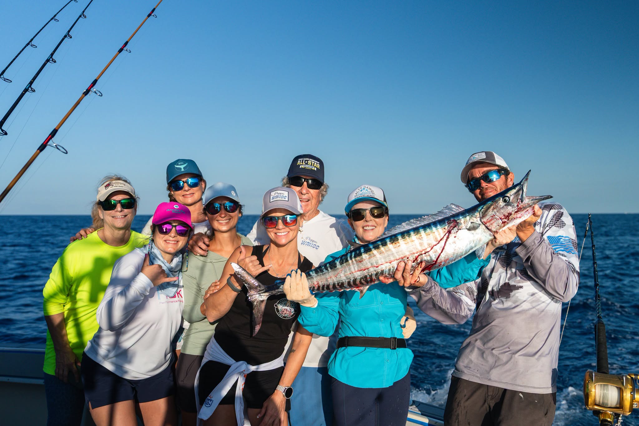 The whole crew holding a wahoo aboard the Poppa Wahoo out of Islamorada