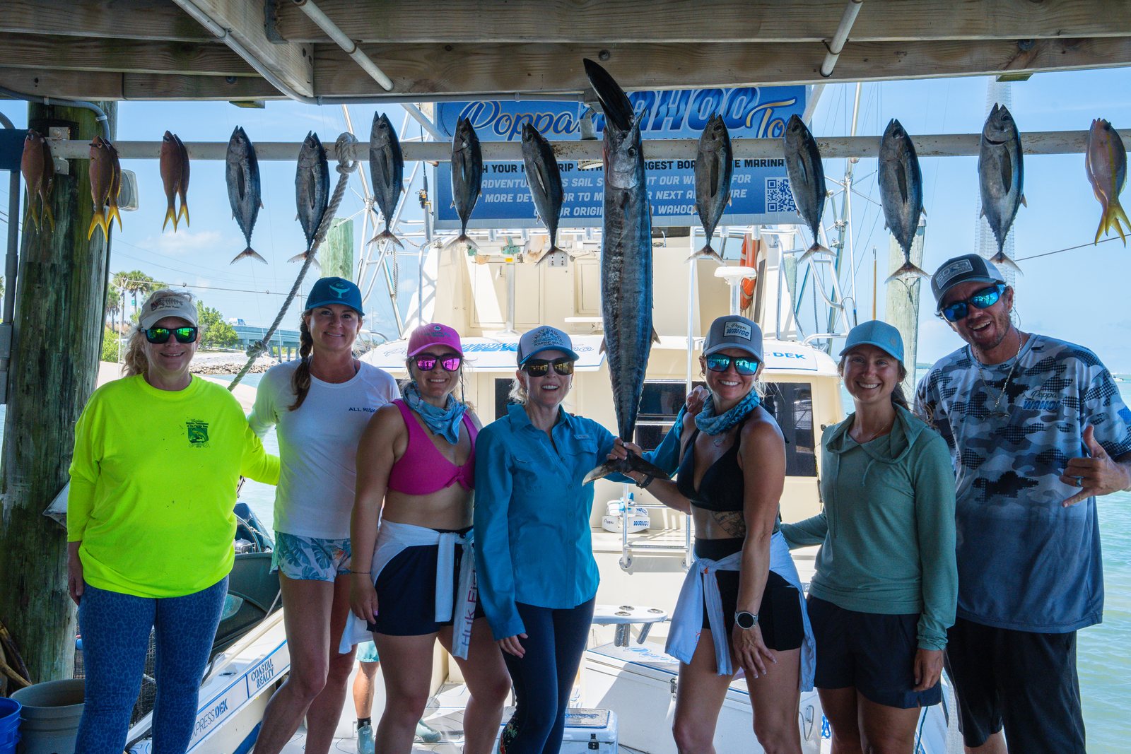 The whole group holding a wahoo along the rail