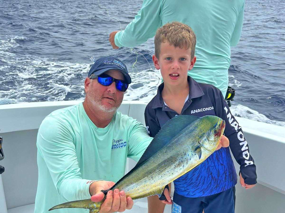 A father and son with a mahi on the back deck