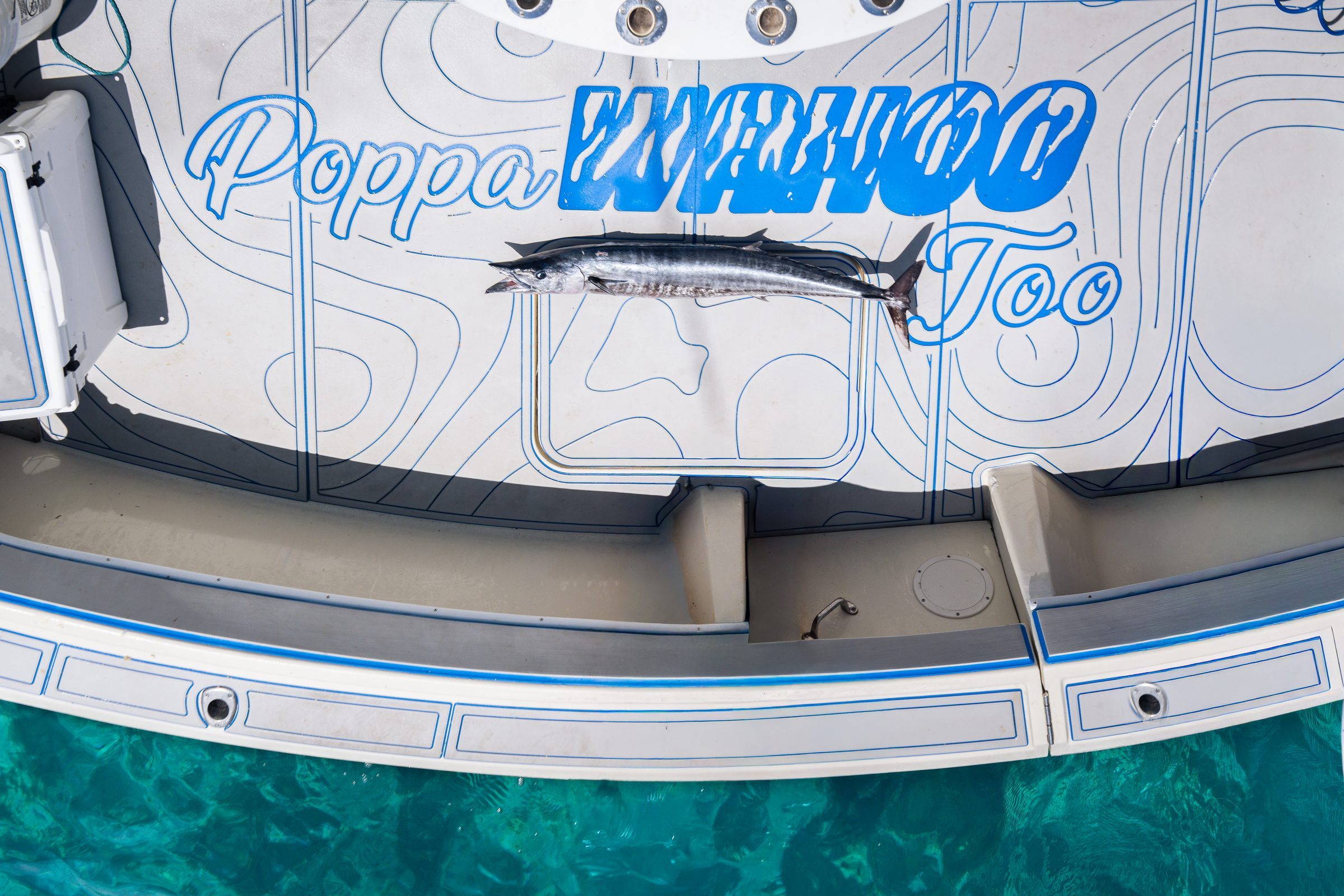 A wahoo laid across the bow of Poppa Wahoo Too on clear water off Islamorada