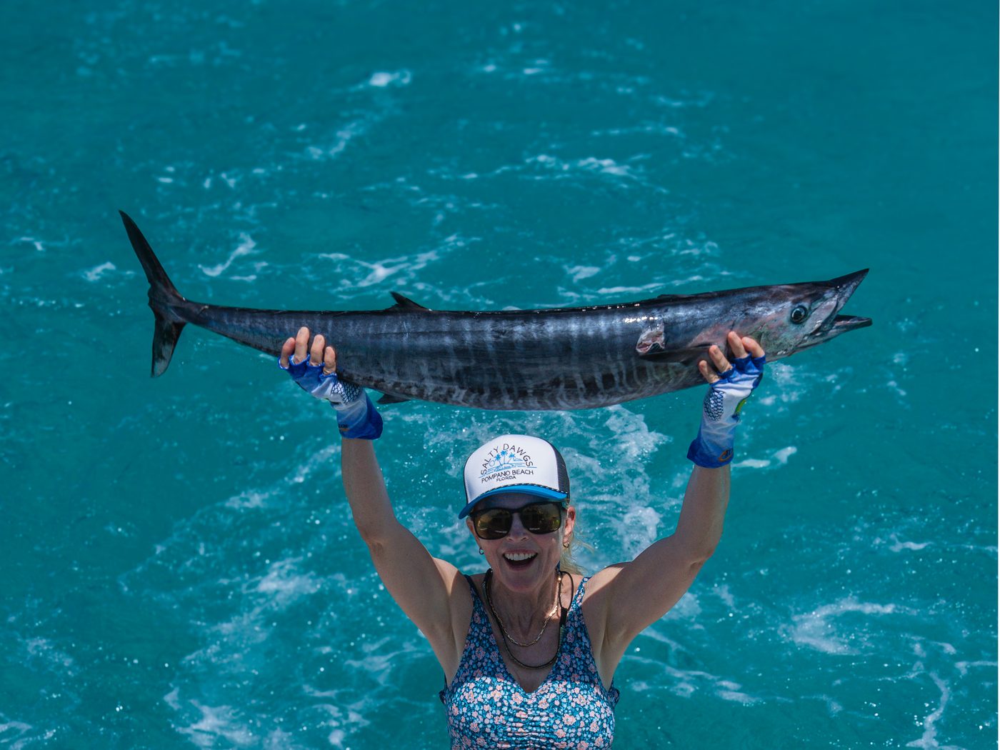 An angler lifting a wahoo overhead on the bow off Islamorada